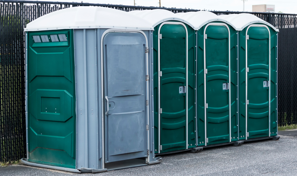 Green,and,gray,potties,set,up,in,a,parking,lot