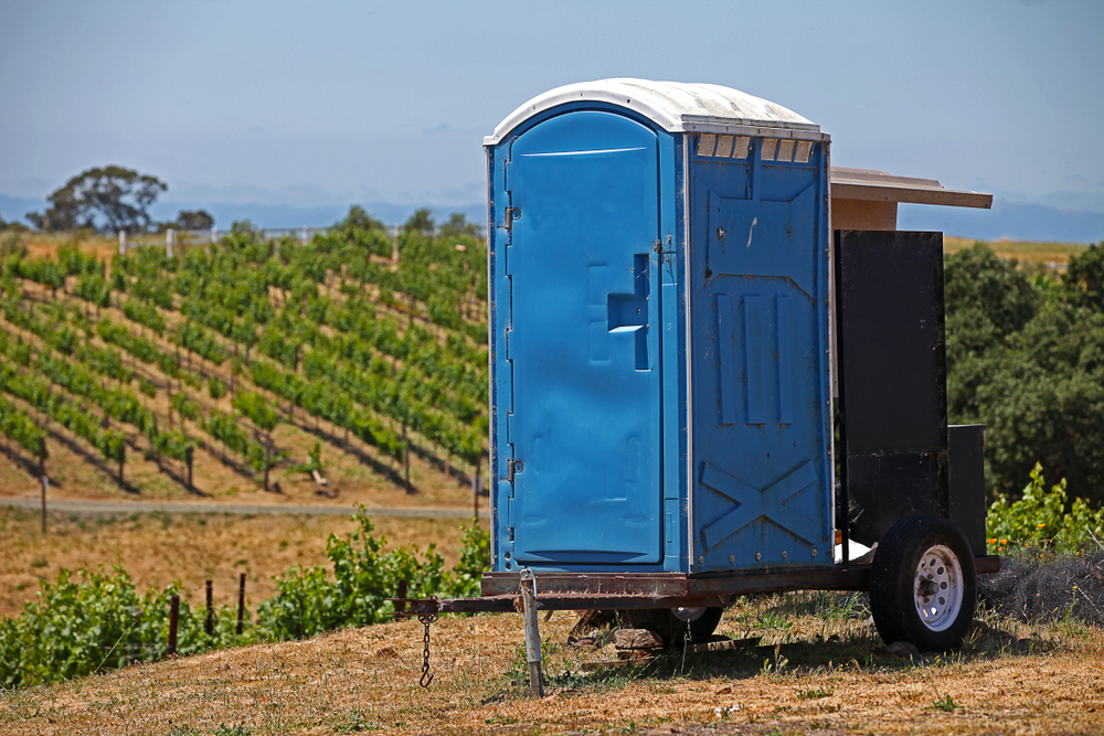 A,blue,portable,bathroom,attached,to,a,two,wheeled,trailer