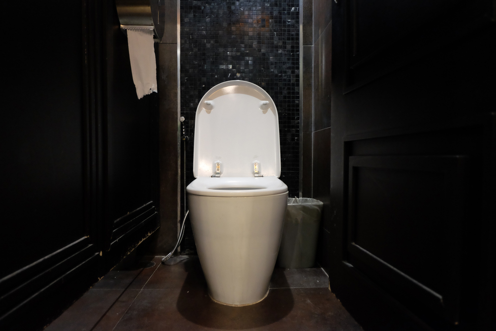 White,toilet,in,black,restroom,with,toilet,paper